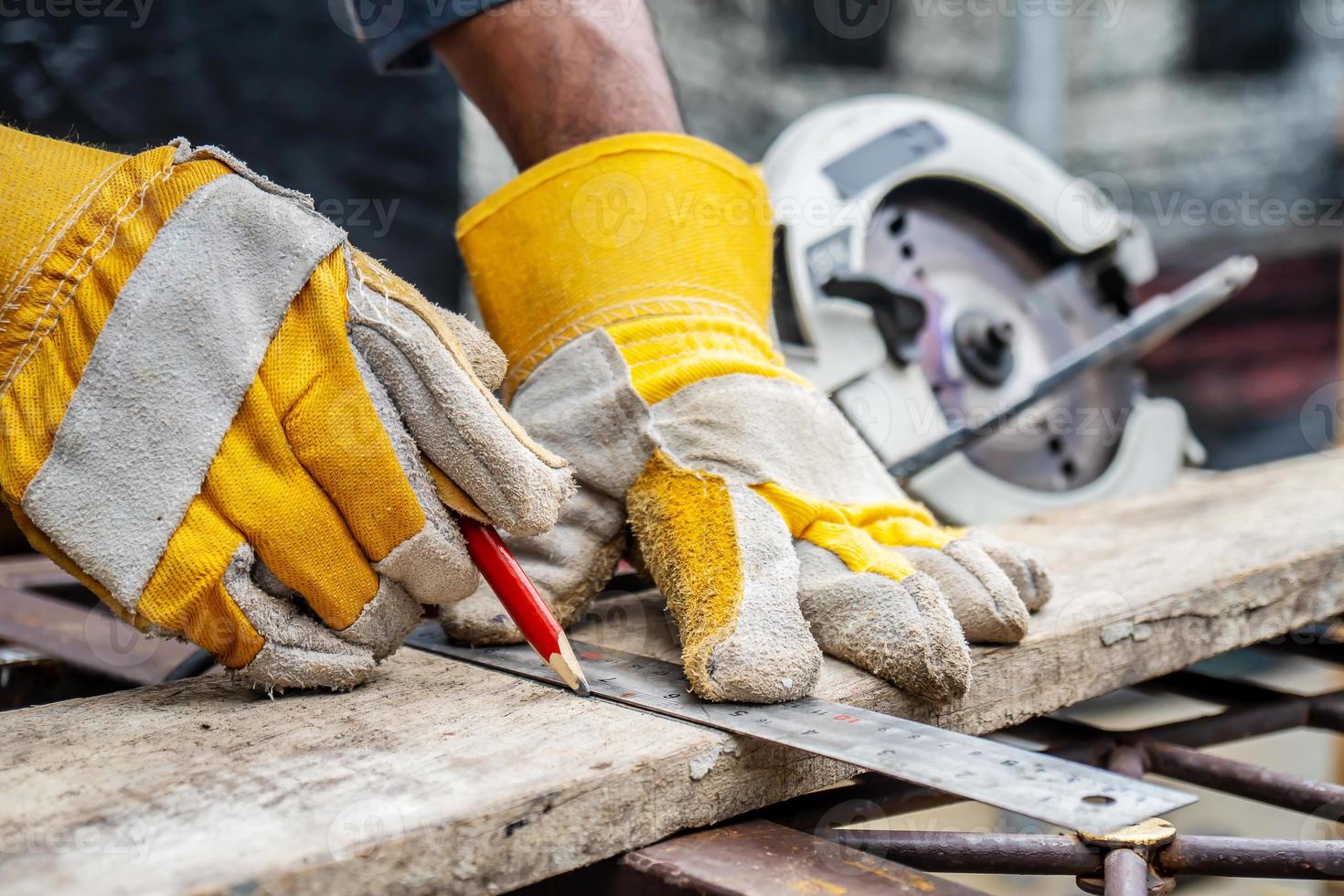 Construction worker wears protective leather gloves, with a pencil and the carpenter's square trace the cutting line on a wooden table. Construction industry, housework do it yourself. photo