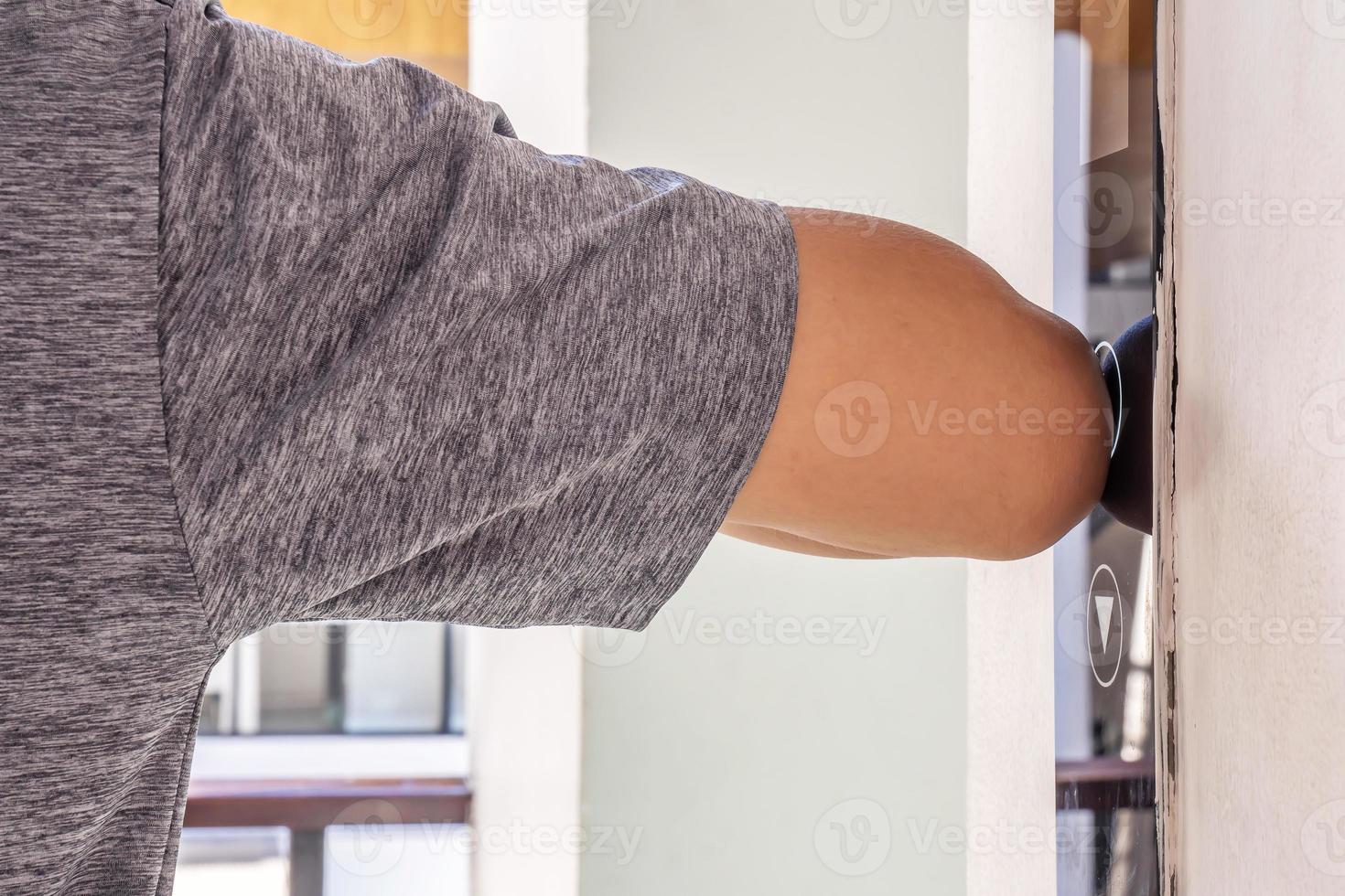 The young man uses an elbow to press the elevator button to prevent infection with Covit19 or corona virus photo