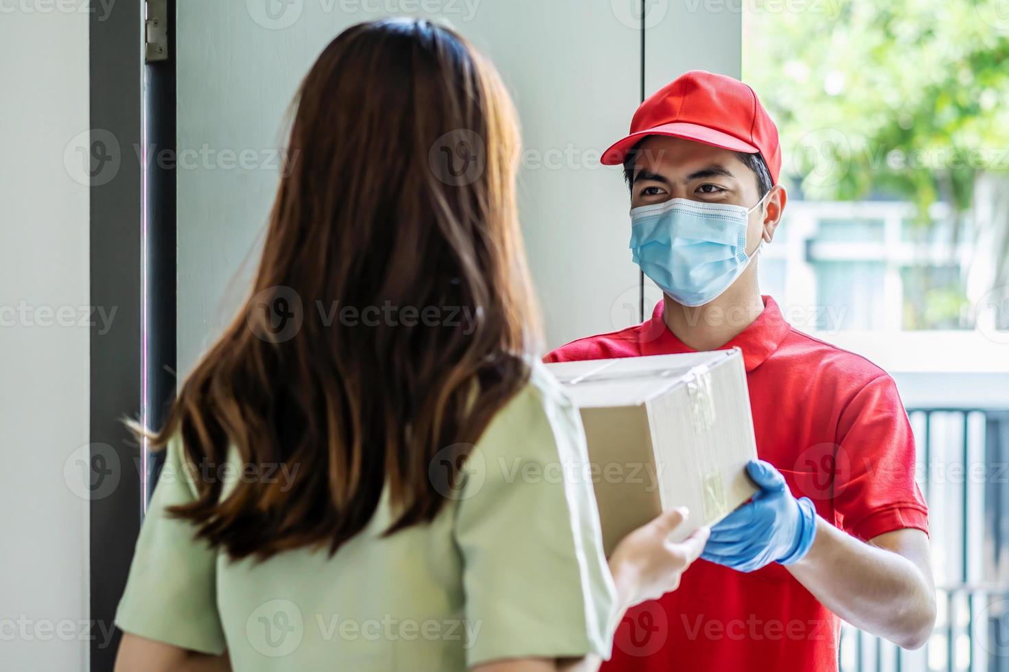 Delivery man in red uniform holdinging parcel boxes to a woman customer - courier service concept photo