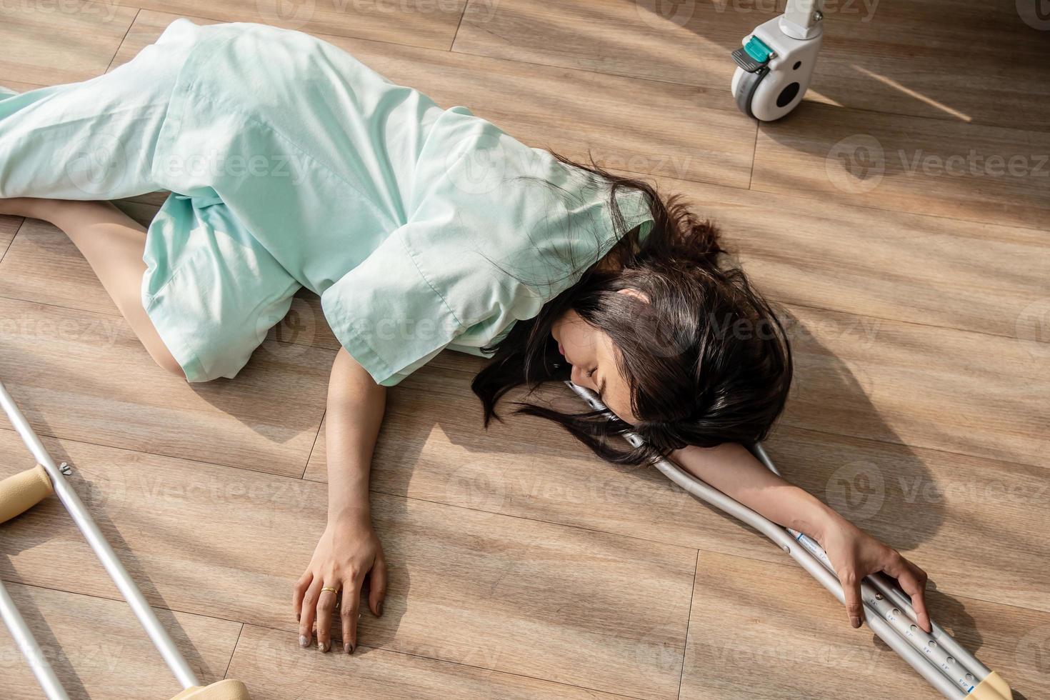 The female patient fell unconscious lying on the floor at hospital. There was a support rod falling to the wooden floor in the sick room, epilepsy, unconsciousness, accident or other health photo