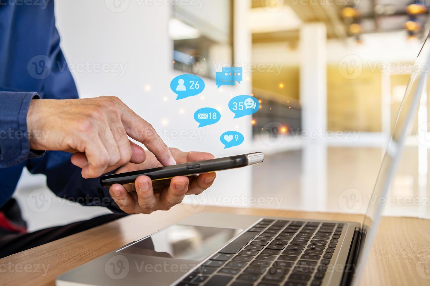 Close-up view of the cell phone in the hands of a man, person using a social media marketing concept on mobile phone with notification icons of like, message, comment and star above smartphone screen photo
