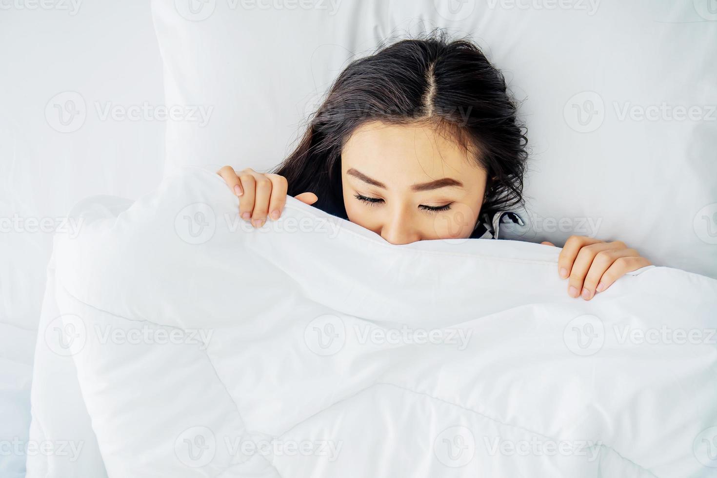 Top view of sleeping asian woman cover face with blanket flat lay. Close-up of young women, sleeping under white blanket and covering half face. Copy space for advertisement photo