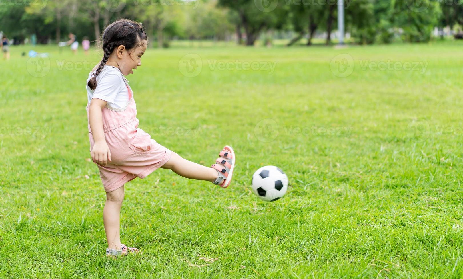 chico deportivo niña feliz pateando una pelota de fútbol, juegos infantiles foto