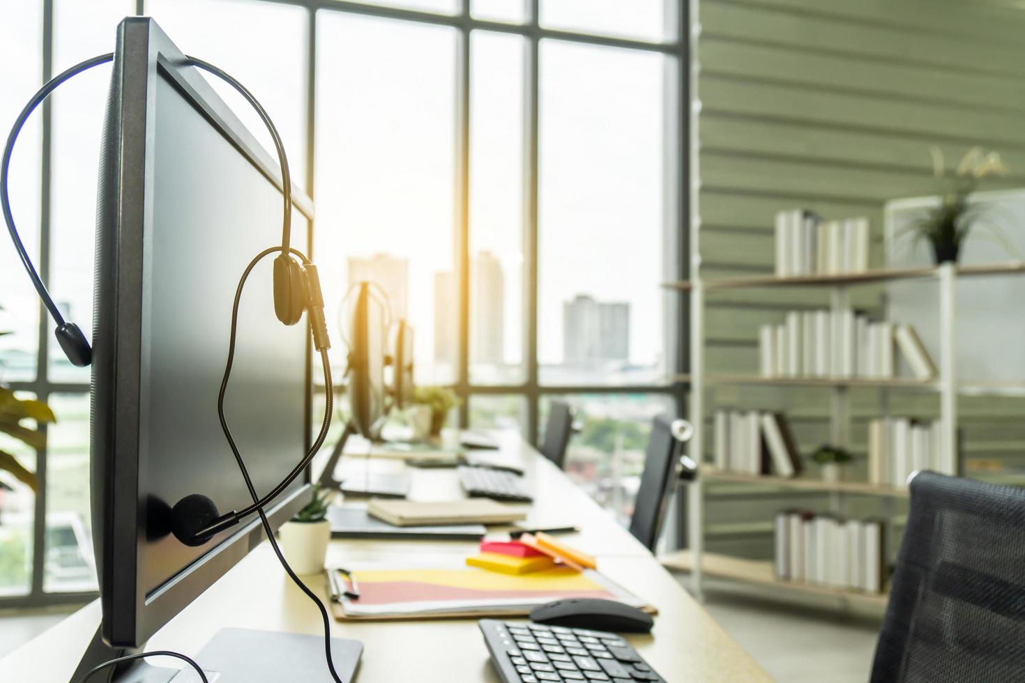 Row of computers with headphones on desk at call center, Communication support, VOIP headset on laptop computer keyboard. photo