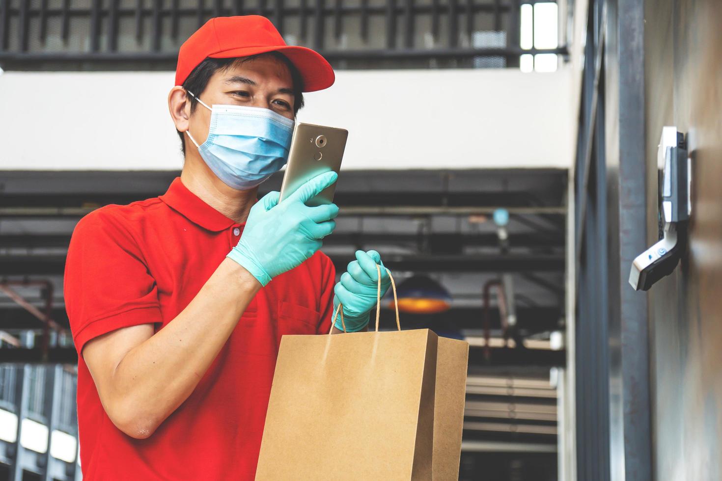 Food delivery, tracking orders, covid-19 and self-quarantine concept. Courier checking client address on phone as bring food order, calling customer, standing office background photo