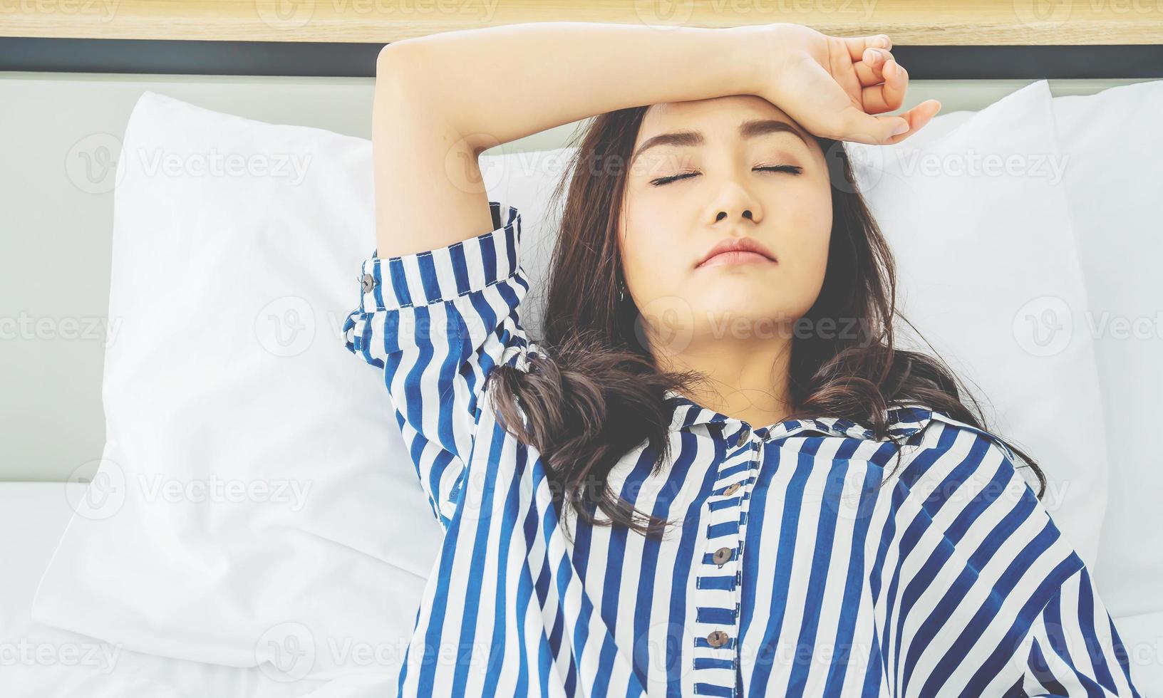 una joven asiática infeliz y pensativa tocándose la frente, sintiéndose triste y solitaria acostada en la cama sola tratando de dormir pensando en problemas, miedos, preocupaciones y desesperanza. foto