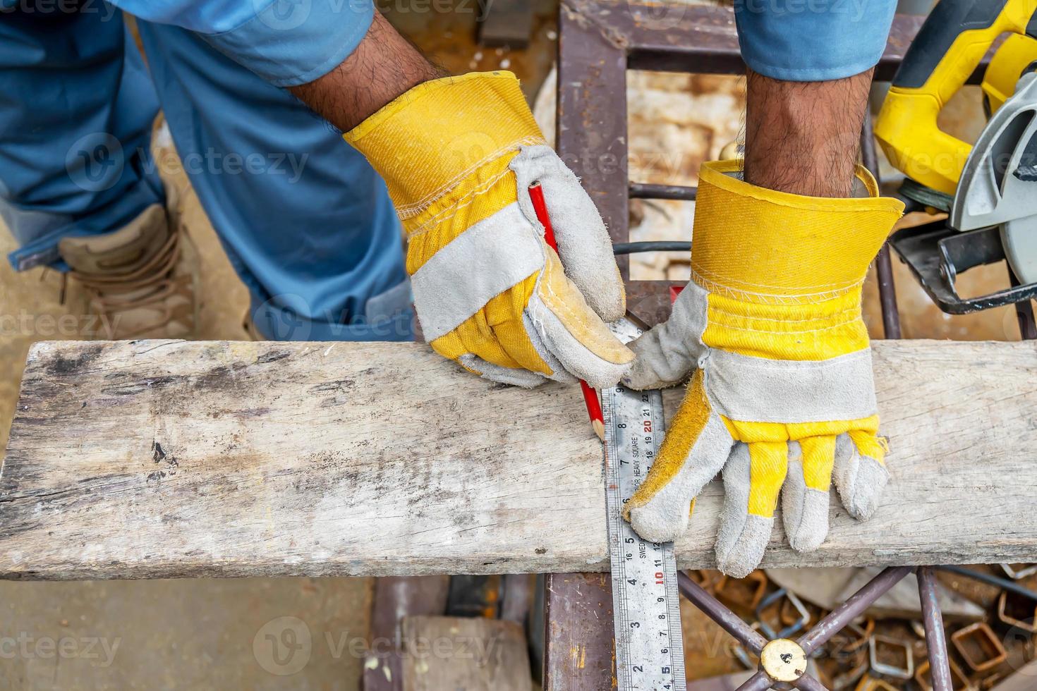 Construction worker wears protective leather gloves, with a pencil and the carpenter's square trace the cutting line on a wooden table. Construction industry, housework do it yourself. photo