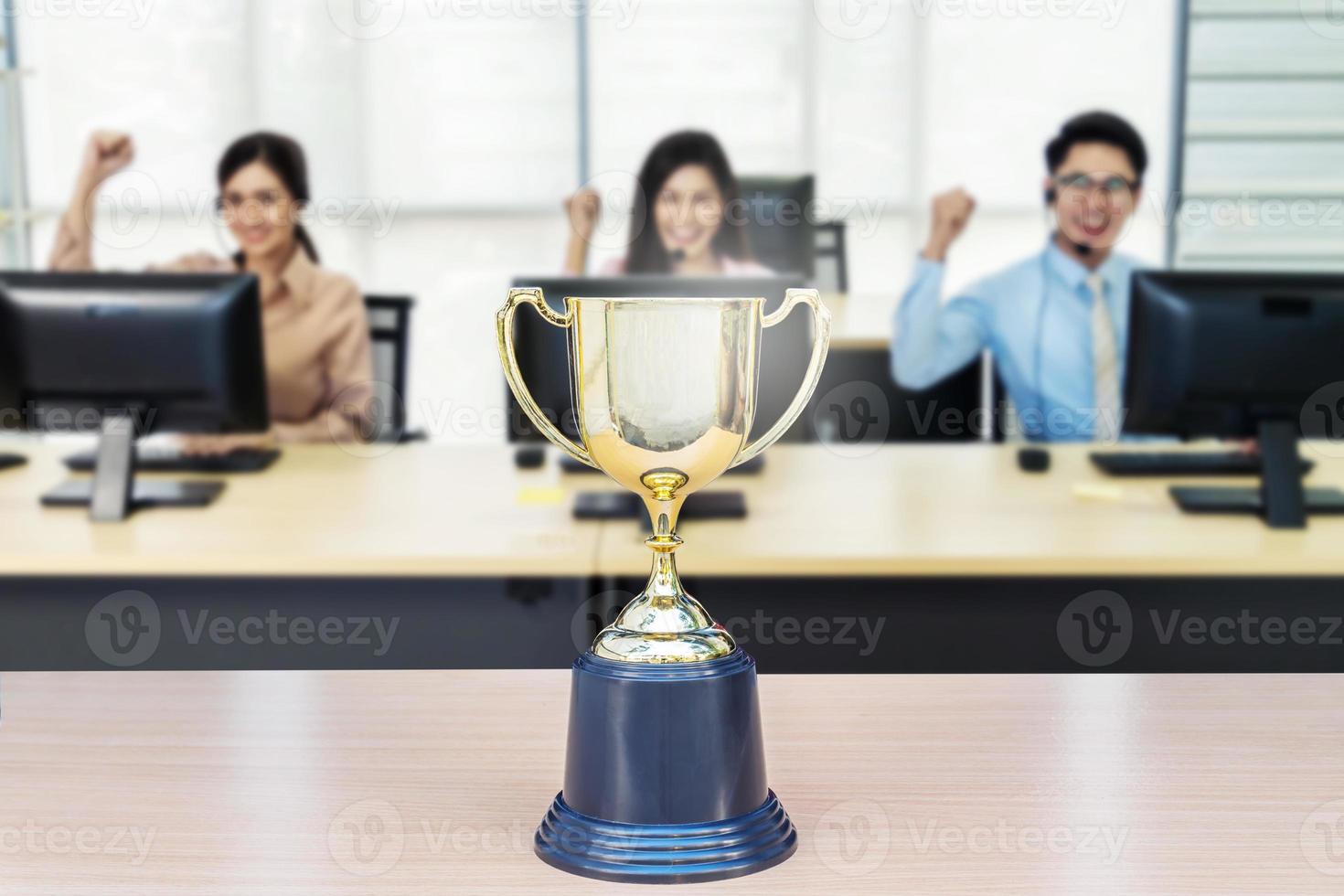 Close up of a trophy in front of a working business people, achieve business concept. photo