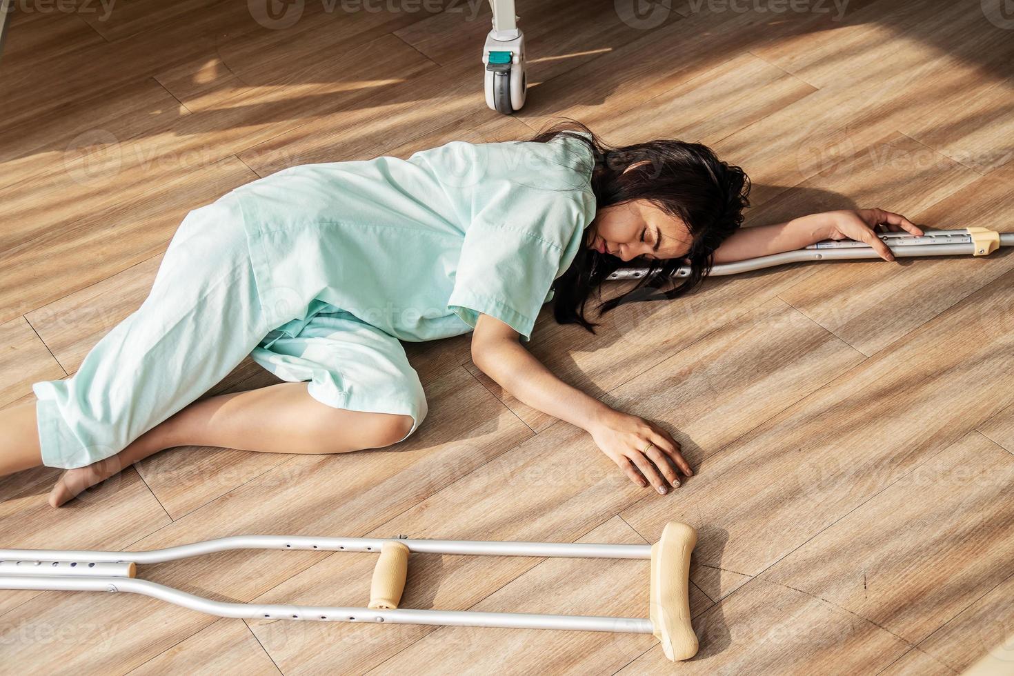 The female patient fell unconscious lying on the floor at hospital. There was a support rod falling to the wooden floor in the sick room, epilepsy, unconsciousness, accident or other health photo