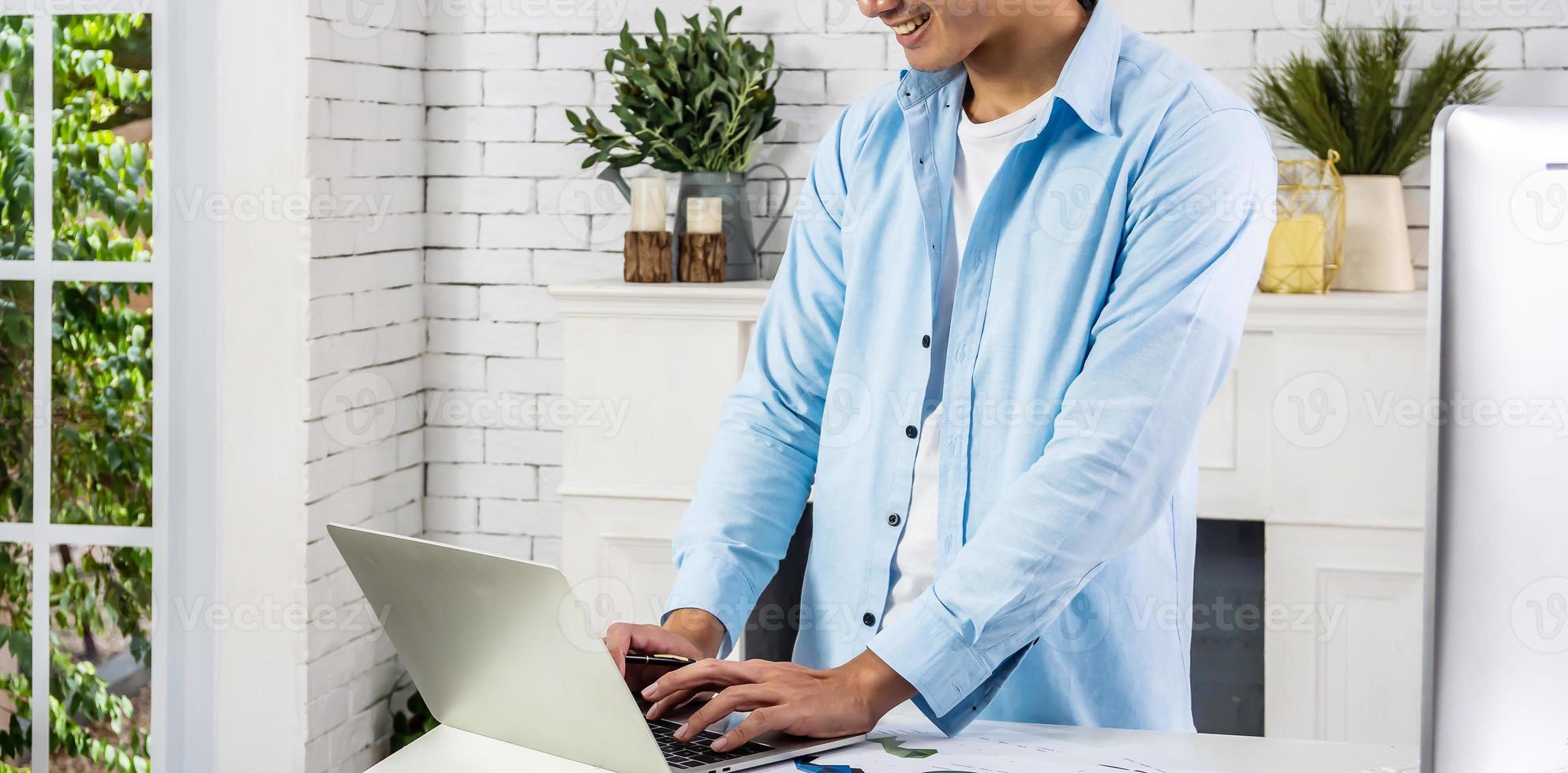 Young smiling happy asian man relaxing connected on internet with laptop computer working and video conference meeting at home.Young creative typing on keyboard.work from home photo