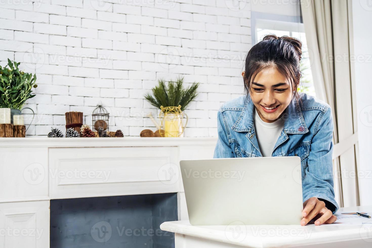 Young smiling happy asian woman relaxing connected on internet with laptop computer working and video conference meeting at home.Young creative typing on keyboard, work from home concept photo