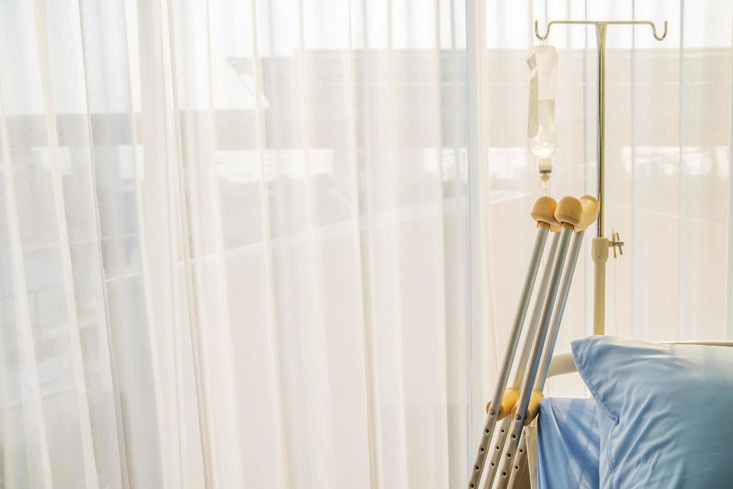 Empty bed with pillow and blanket and intravenous stand and walking stick, Walking stick cane used by disable patient for balancing, Healthcare,medical insurance and Physical therapy concept. photo