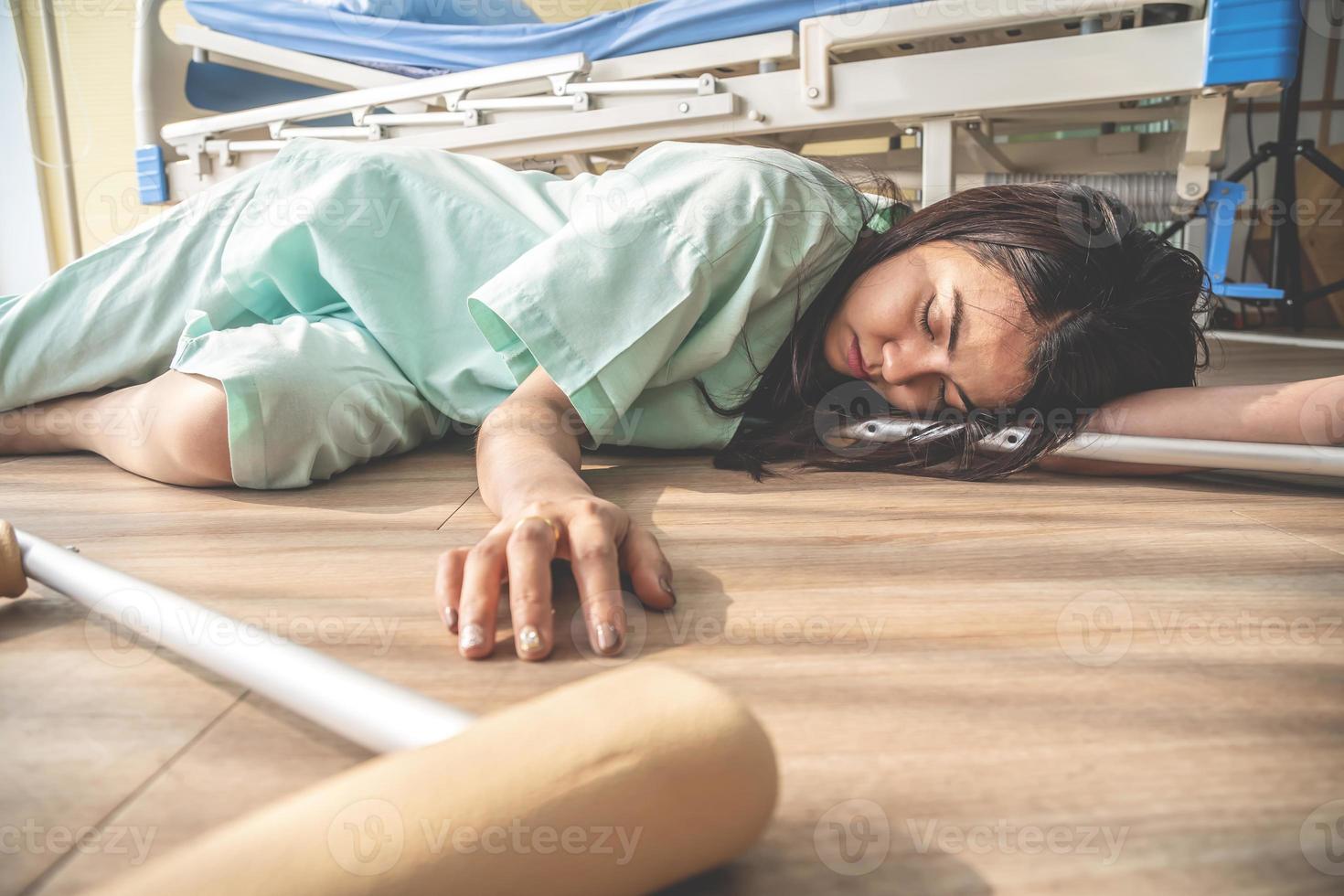 The female patient fell unconscious lying on the floor at hospital. There was a support rod falling to the wooden floor in the sick room, epilepsy, unconsciousness, accident or other health photo