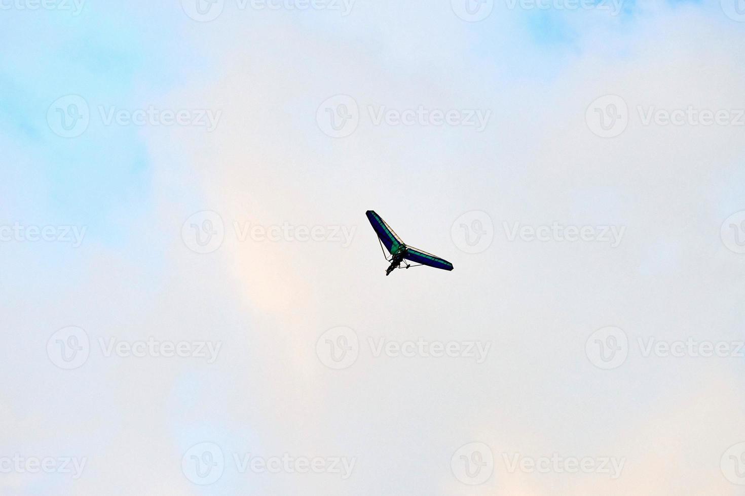 Powered hang glider flying in blue sky, motorized hang glider overhead view, copy space photo