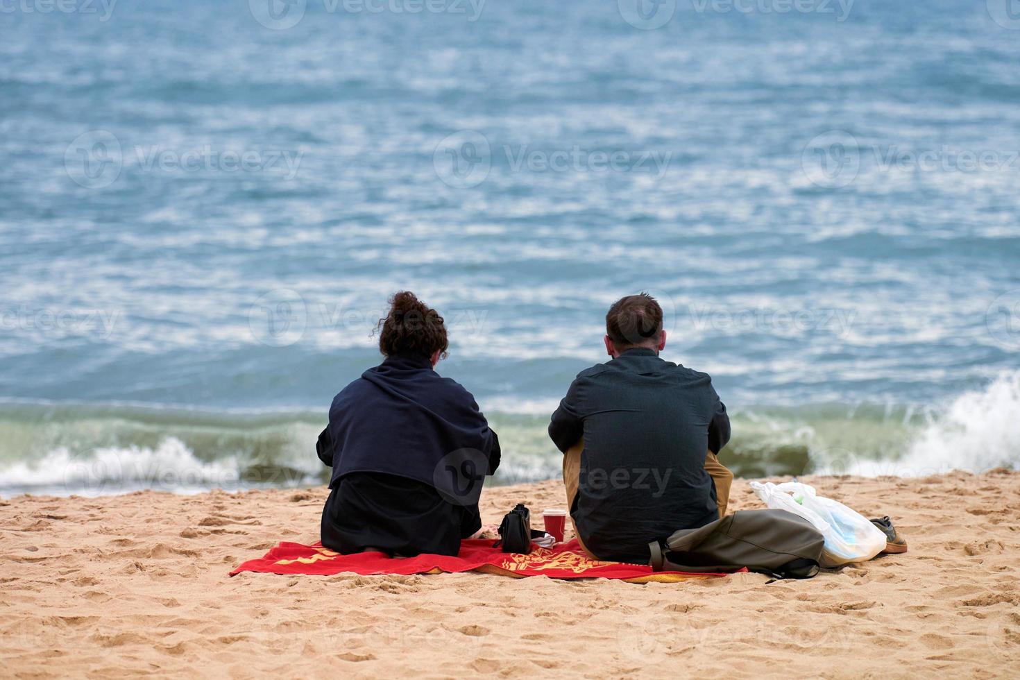 Romantic picnic love couple sitting on sea beach, candid couple talking about romantic relationship photo