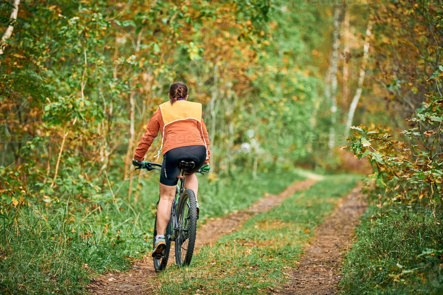 Female mountain biker riding on bike in nature, off-road trail, sports, fitness, health photo