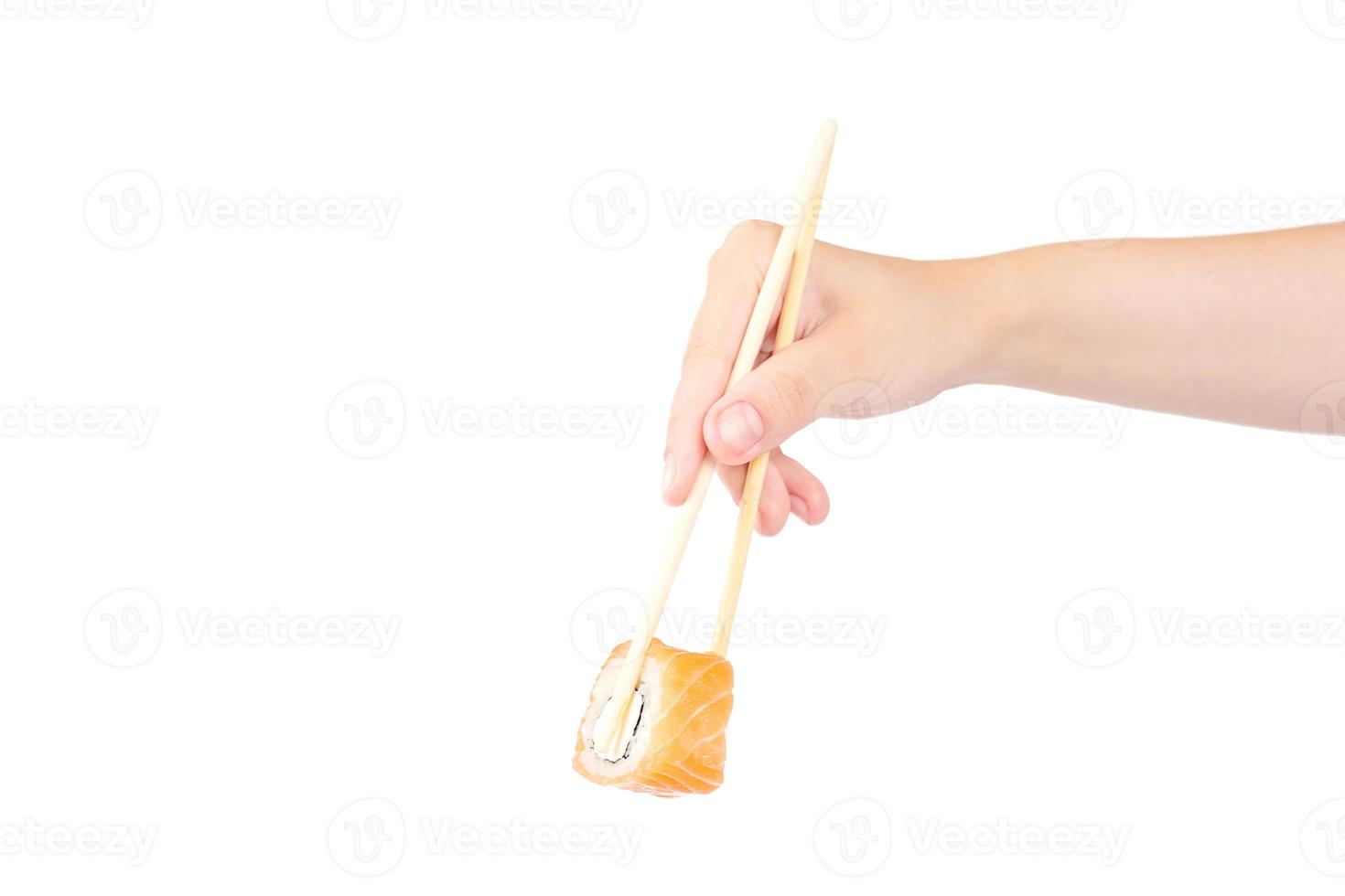 Female hand holding Philadelphia maki roll with bamboo chopsticks isolated on white background photo