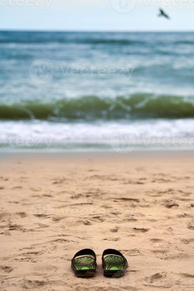 sandalias en la playa de arena, hermoso fondo del mar báltico, concepto de ahogamiento foto