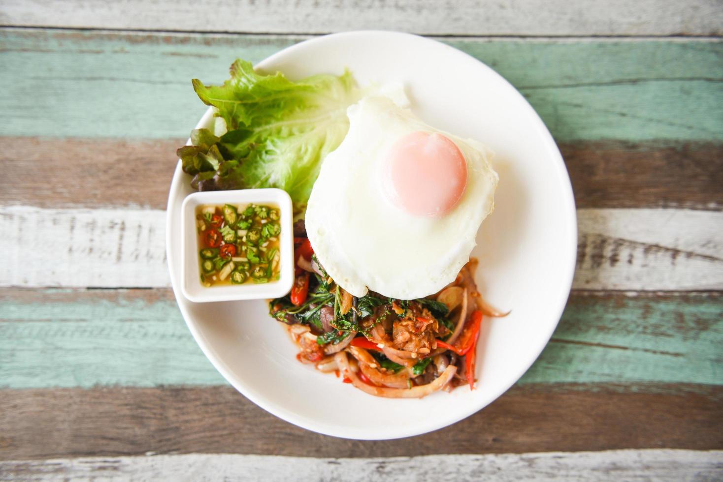 Thai food spicy fried recipe with vegetables and chili sauce , top view - Rice topped with stir fried pork beef meat with holy basil and fried egg photo