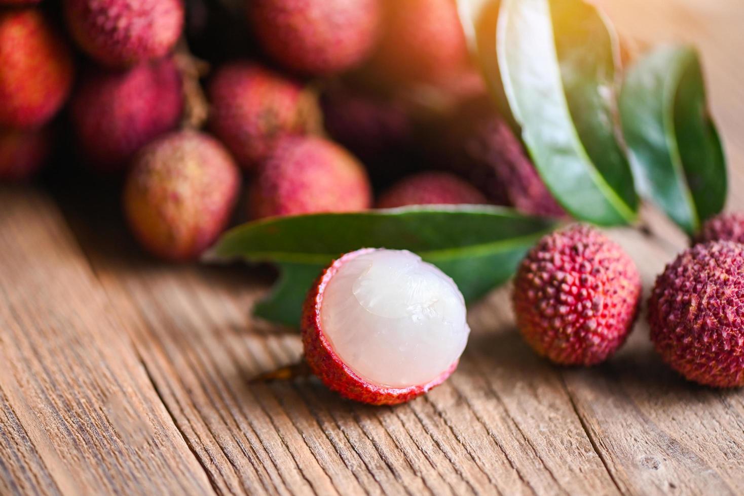 Lychee fruit and green leaf on wooden background, fresh ripe lychee peeled from lychee tree at tropical fruit Thailand in summer photo