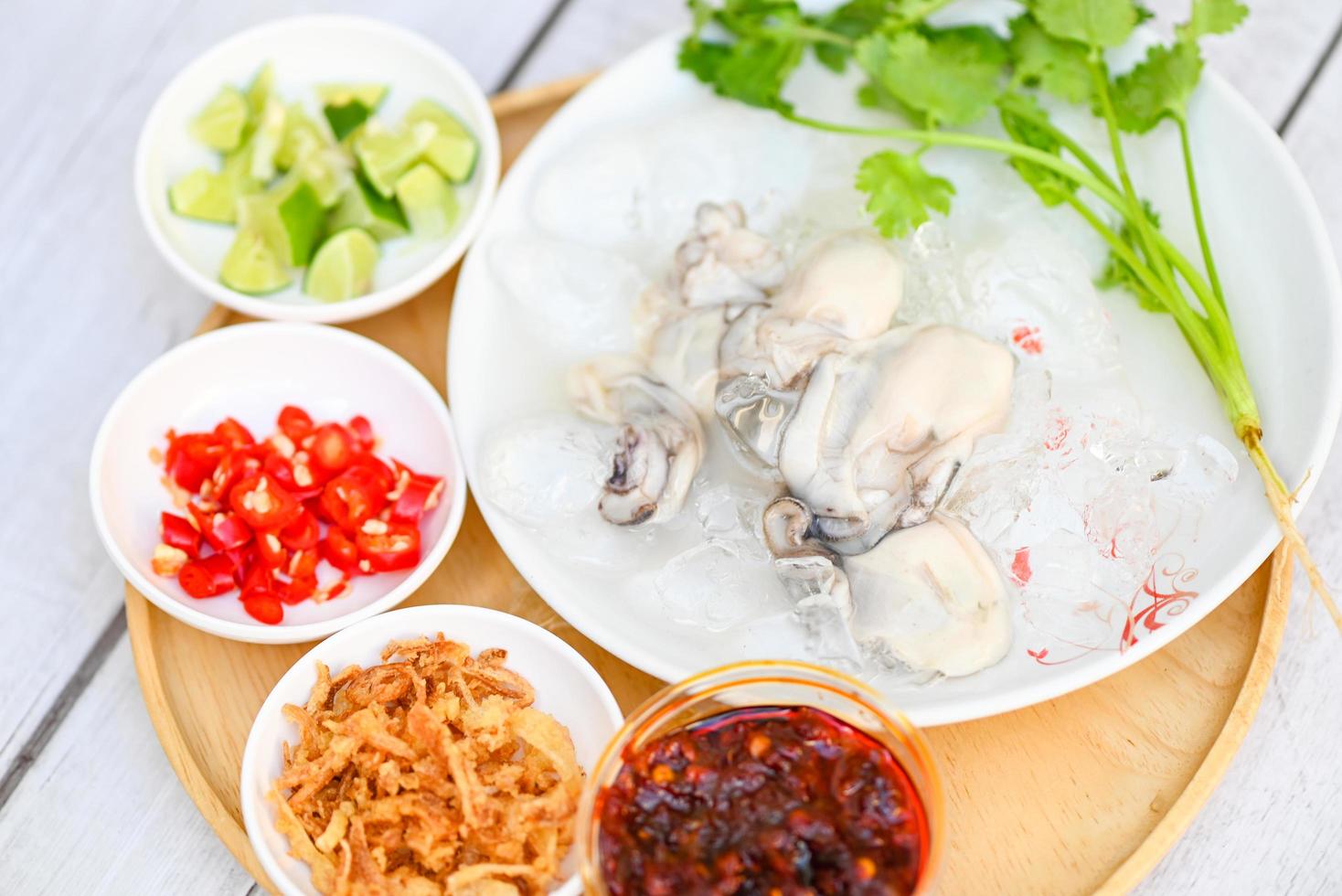 seafood plate fresh oyster on white plate background , oyster on ice with lemon lime chili sauce fried onion and seafood sauce Thai food photo