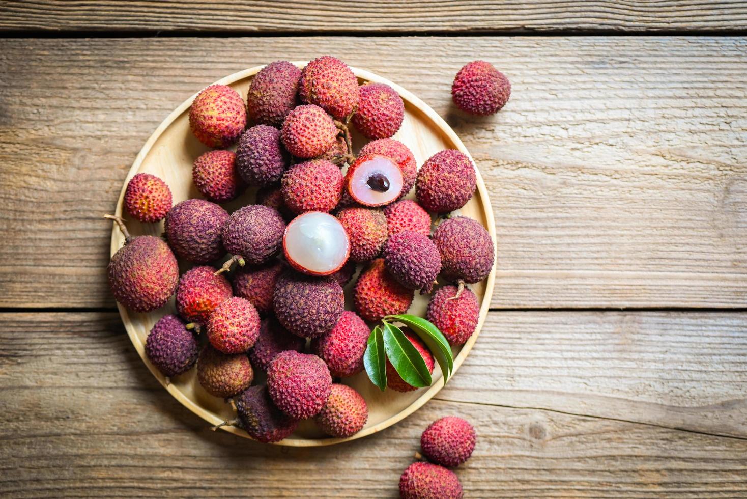 Lychee frui with green leaf on wooden plate background top view, fresh ripe lychee peeled from lychee tree at tropical fruit Thailand in summer photo