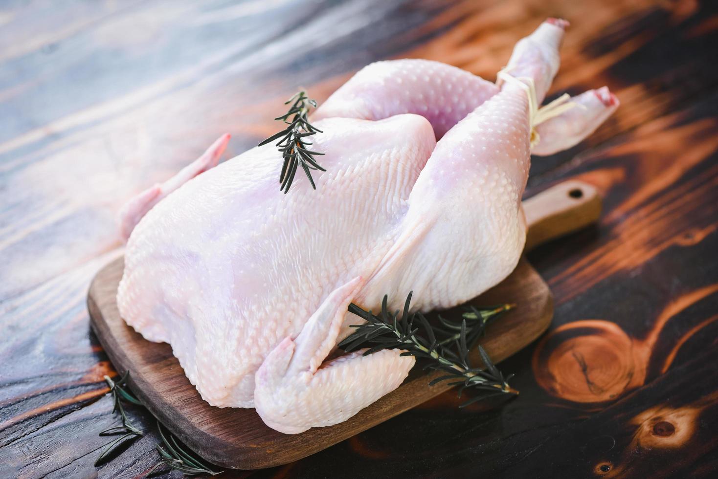 Rosemary chicken meat - fresh raw chicken whole on wooden board on white wood background photo