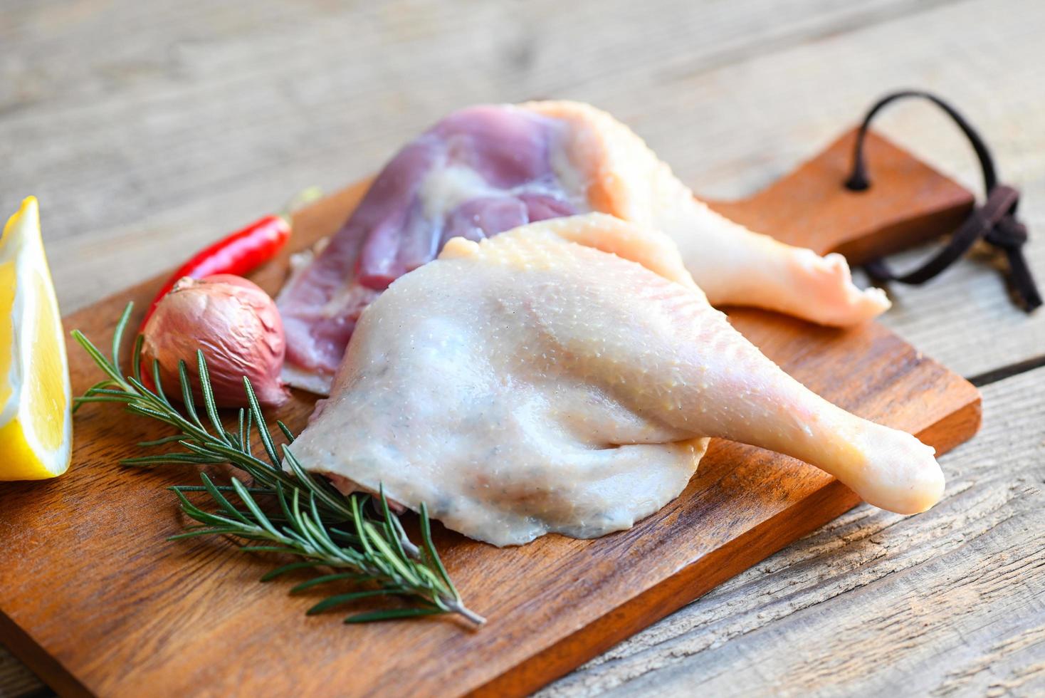 Raw duck legs with herb spices ready to cook on wooden cutting board, Fresh duck meat for food photo