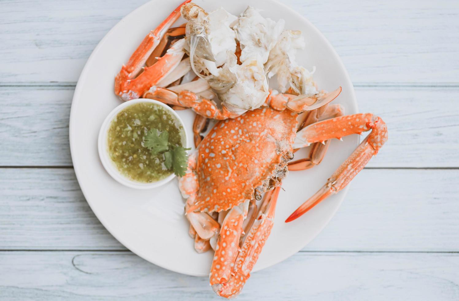 seafood plate fresh crab cooking on white plate background , blue swimming crab meat claw served on a food table - cooking steamed crab with seafood sauce top view photo