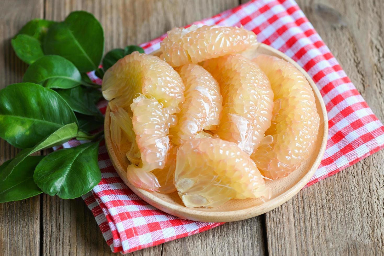 pomelo fruit on wooden plate, fresh green pomelo peeled on wooden and green leaf frome pomelo tree , pummelo , grapefruit in summer tropical fruit  in thailand photo