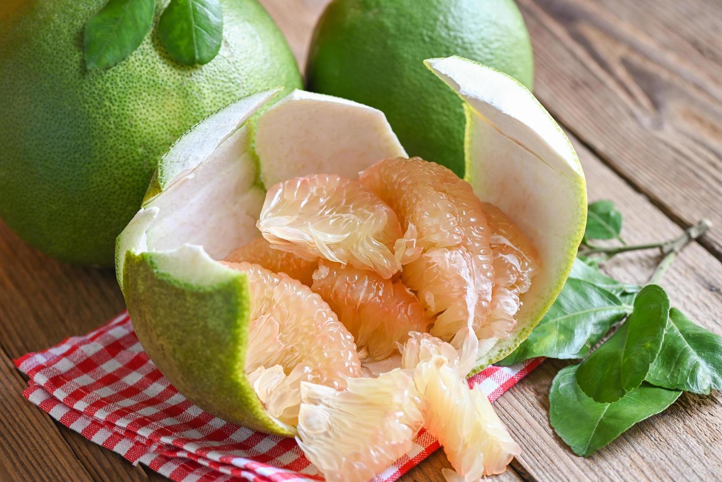 pomelo fruit on wooden background, fresh green pomelo peeled on pomelo skin and leaf frome pomelo tree , pummelo , grapefruit in summer tropical fruit  in thailand photo