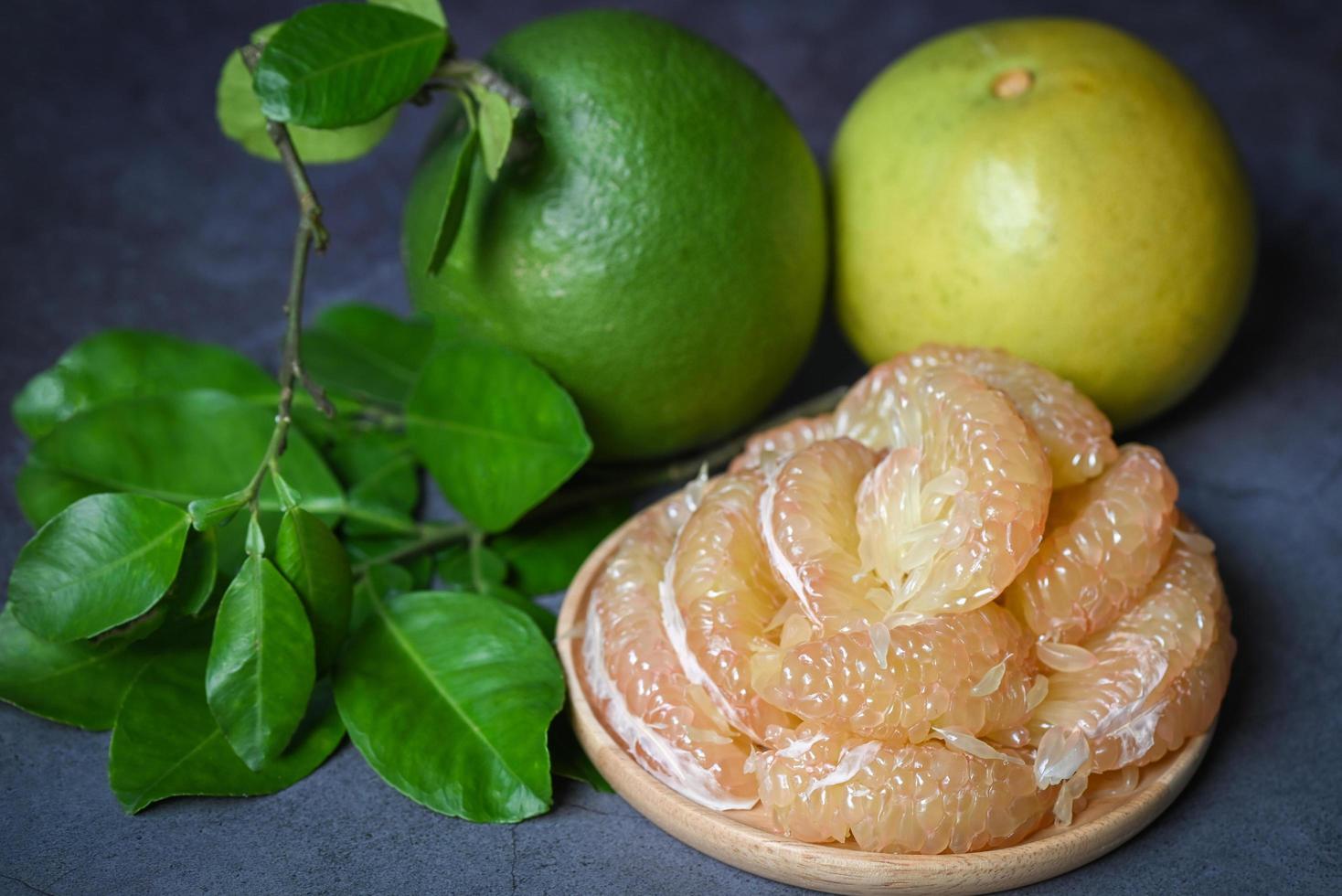 pomelo fruit on plate and dark background, fresh green pomelo peeled on plate and green leaf frome pomelo tree , pummelo , grapefruit in summer tropical fruit  in thailand photo