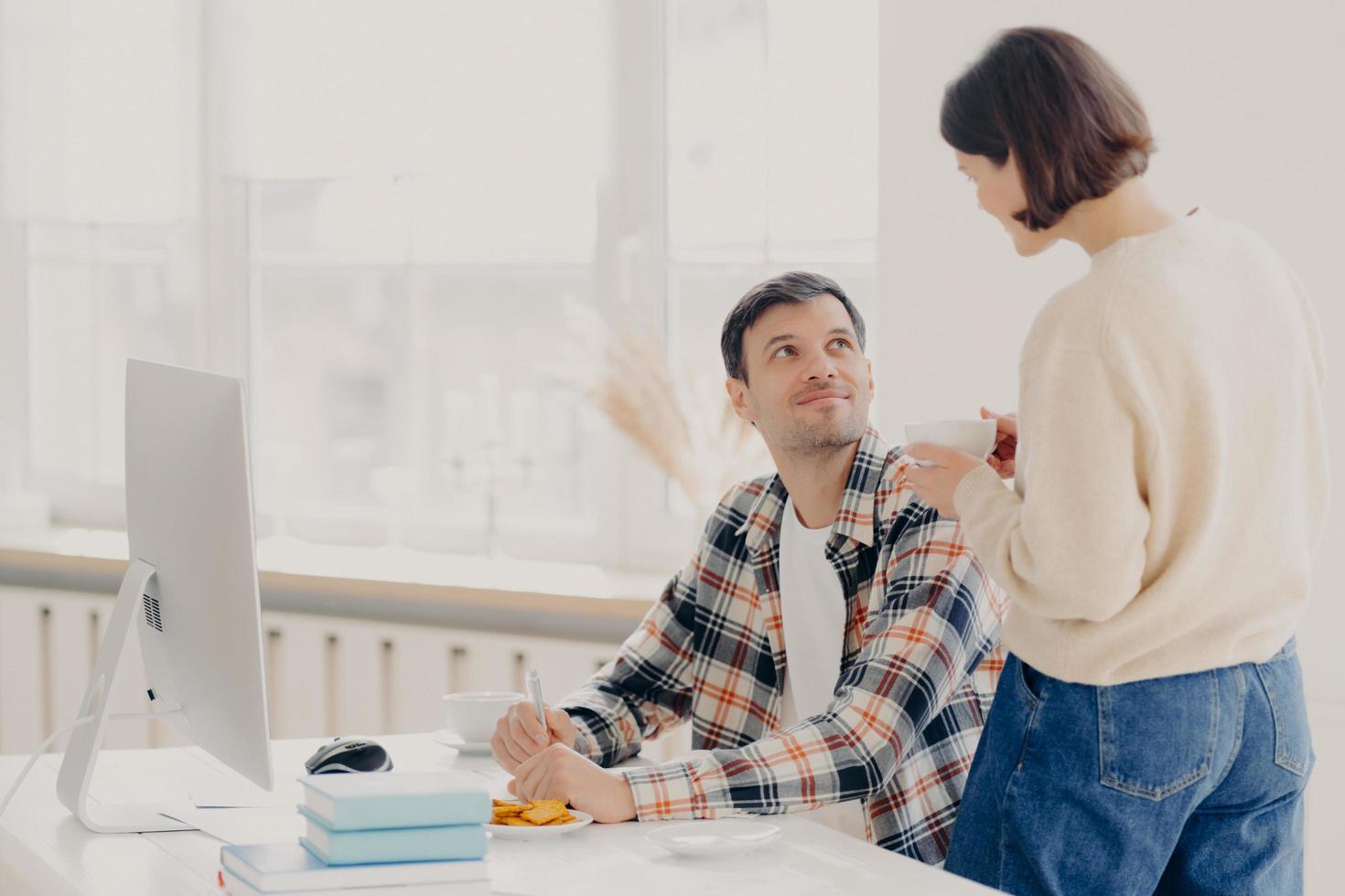 concepto de familia, papeleo y tecnología. el esposo y la esposa estudian el acuerdo del contrato, leen los términos y condiciones, discuten las facturas domésticas, beben café, el hombre posa en el escritorio con una computadora moderna foto