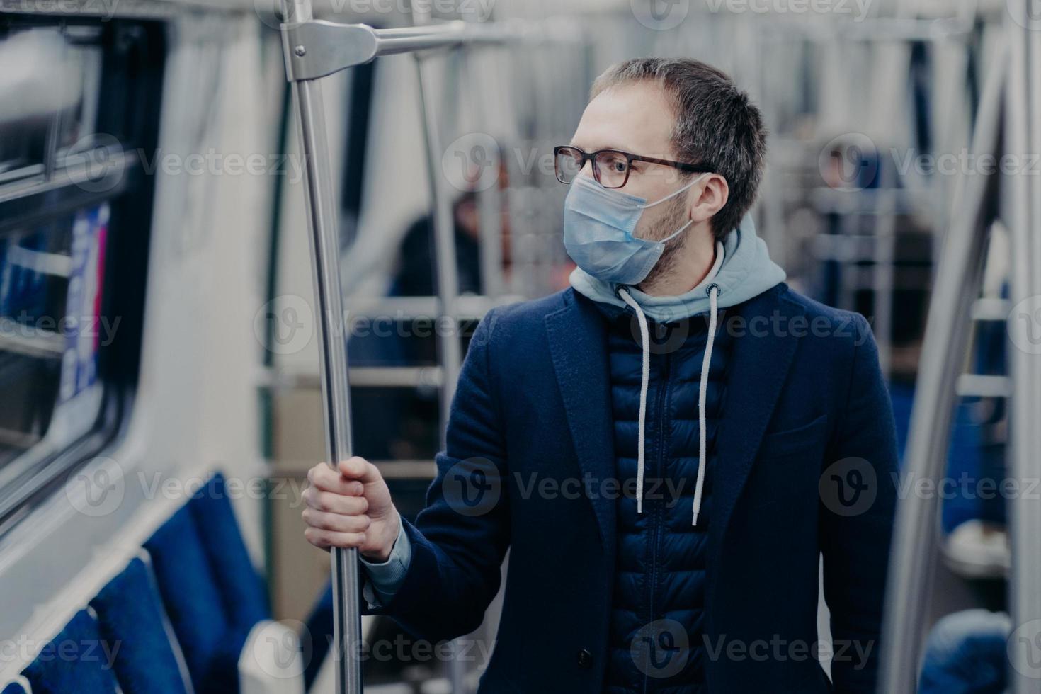 Prevention in public transport, health awareness for pandemic protection. Young man wears medical mask while travels by urban train, protects himself from virus. Covid-19 outbreak in Europe. photo