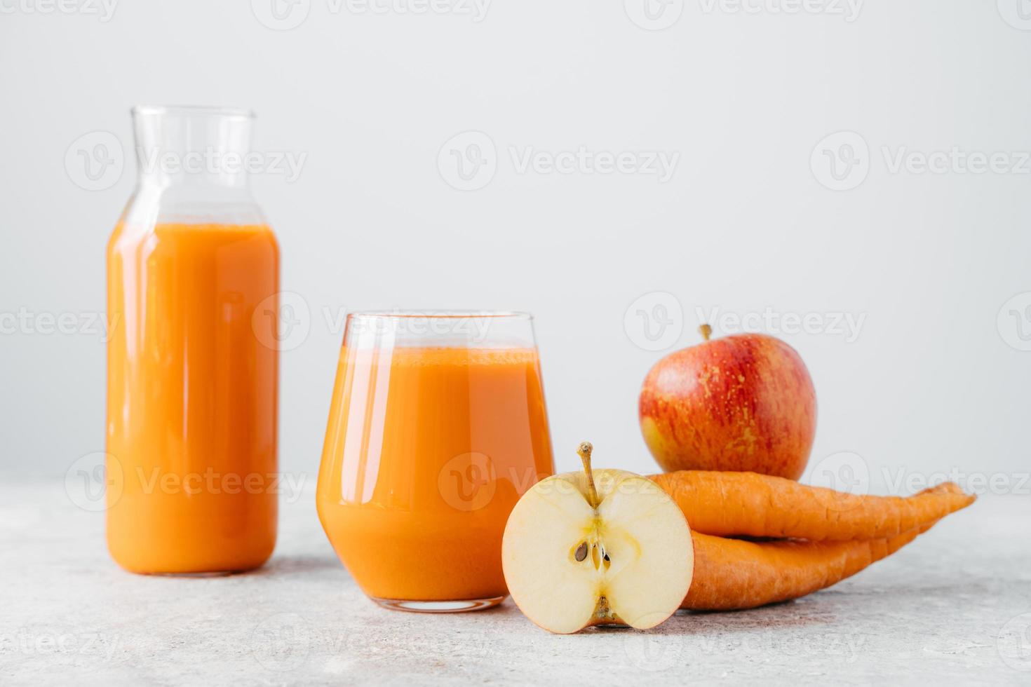 bebida de desintoxicación en frasco de vidrio, rodaja de manzana y zanahoria sobre fondo blanco. refrescante bebida casera de zanahoria natural, frutas y verduras maduras. foto