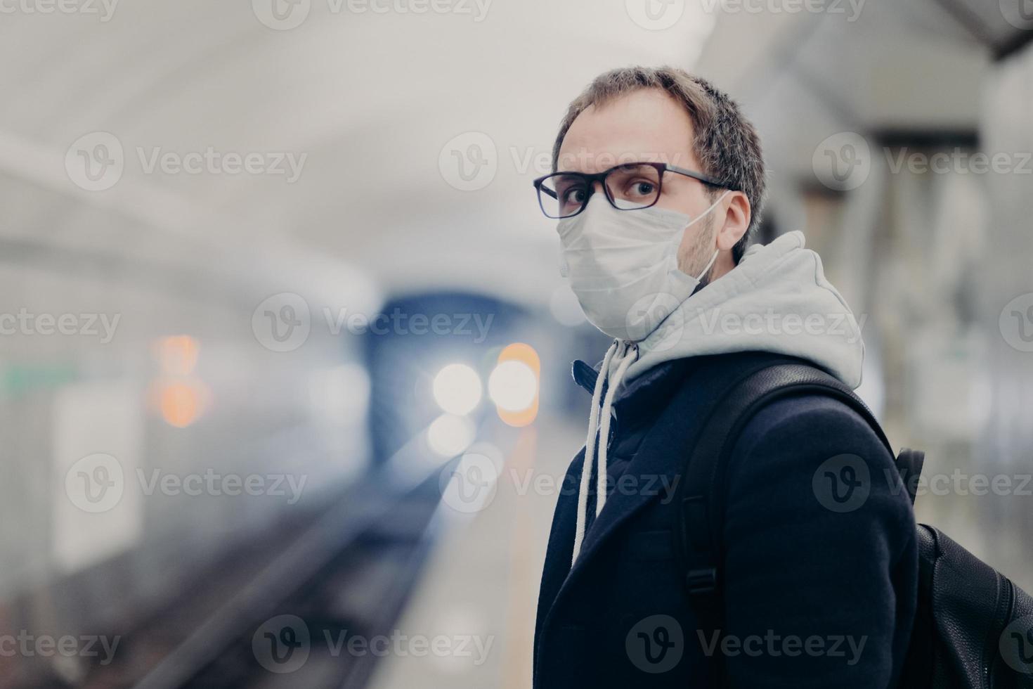 Coronavirus crisis. Male follows quarantine rules wears protective medical mask, travels in public transport cares about health during epidemic or pandemic. Danger of catching virus in city transport photo