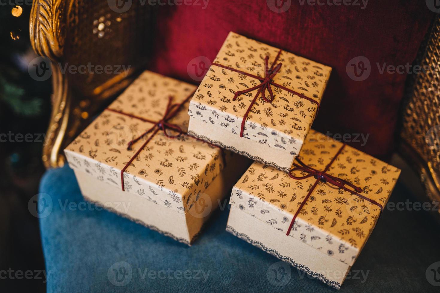 Wrapped gift boxes lie on armchair. Prepared surrpise on birthday or some other holiday. Horizontal picture of three present boxes with ribbons. Celebration and holiday concept. photo