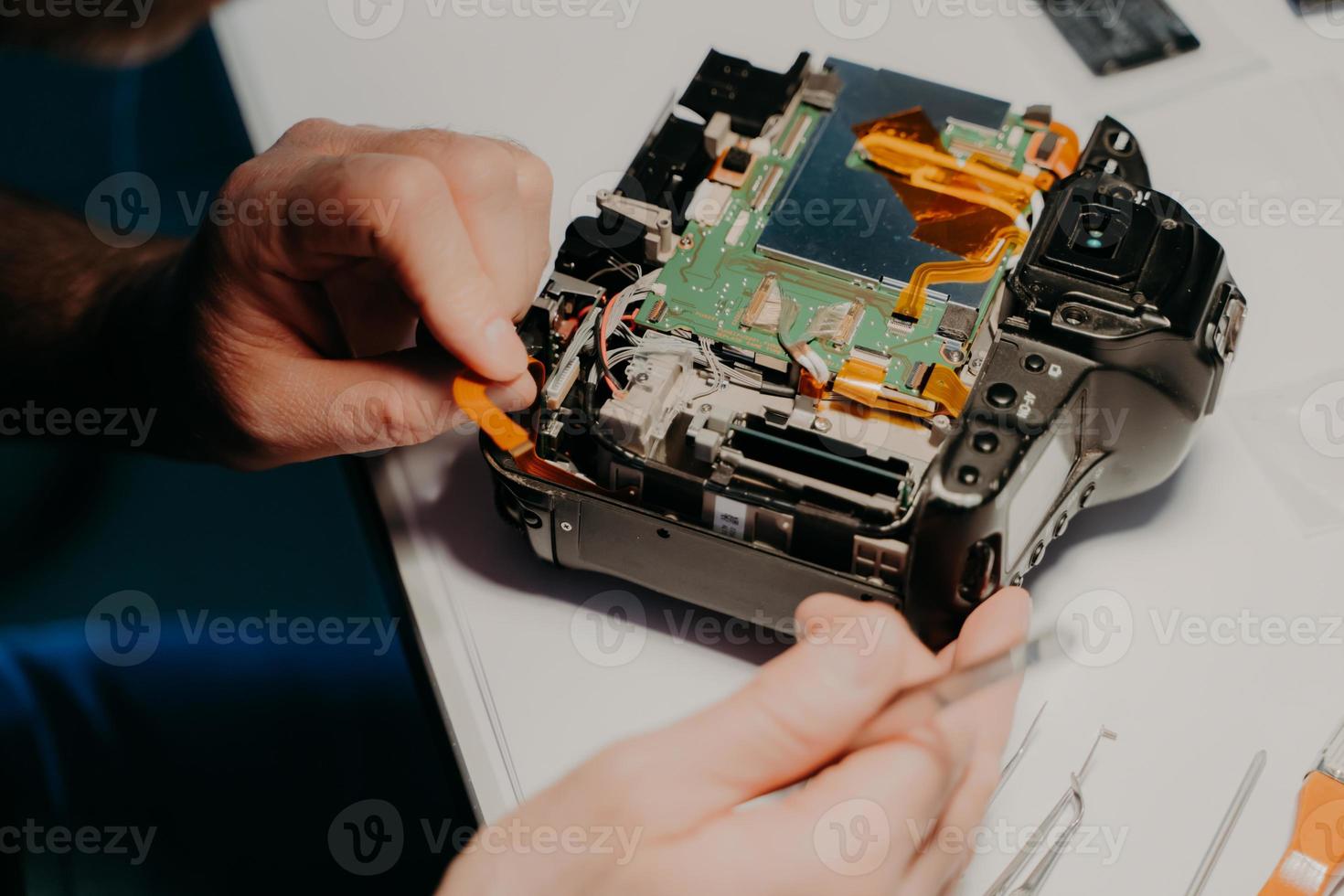 el especialista trabaja en el centro de servicio, utiliza herramientas profesionales. equipo fotográfico en mesa blanca. concepto de reparación profesional. de cerca foto