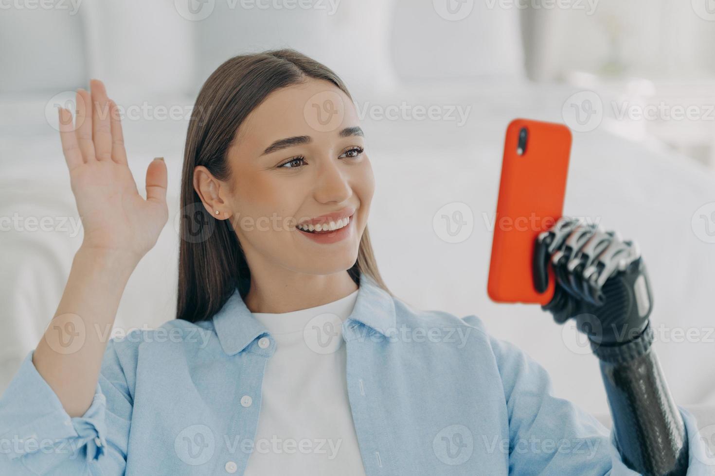 Young disabled woman has video call on phone. European girl is holding phone and taking selfie. photo