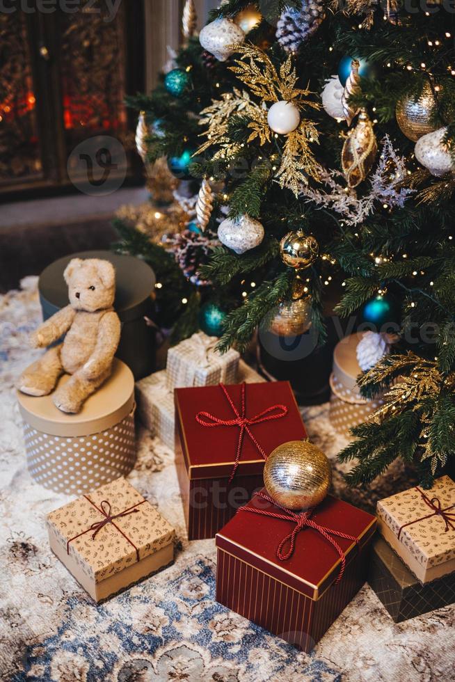 imagen vertical del árbol de navidad decorado con bolas y muchos regalos bajo el abeto. momentos agradables y evento festivo. composición de pila con regalos. vacaciones de año nuevo. foto