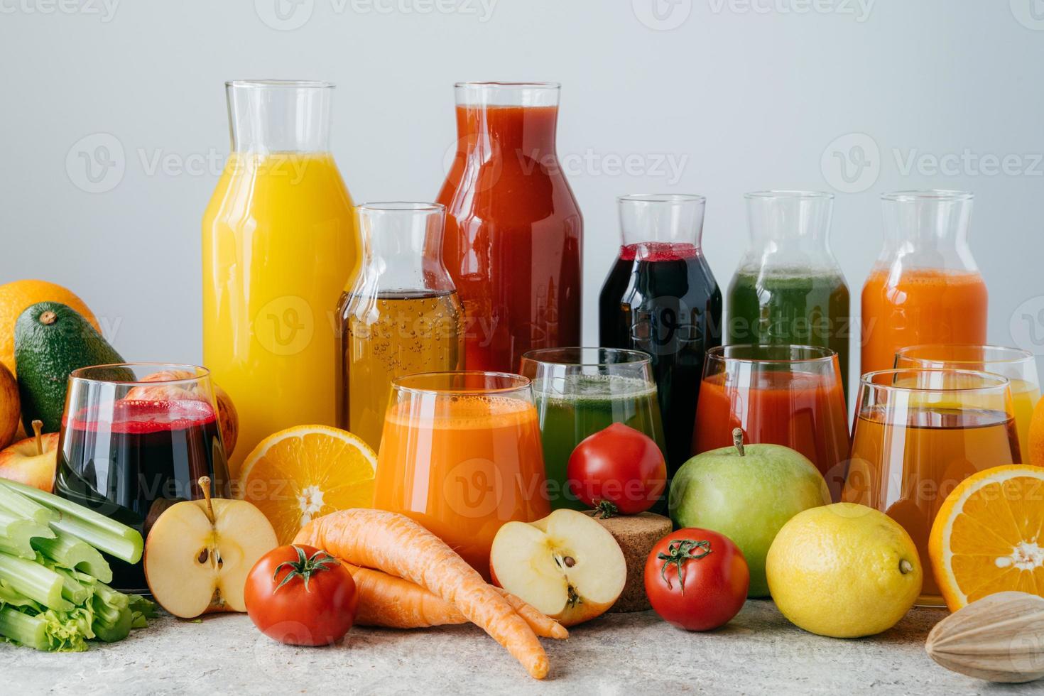Horizontal shot of squeezed vegetables and fruits in glass bottles. Set of colorful fresh apples, lemon, orange, tomatoes and celery against white background. Healthy food and drink concept. photo