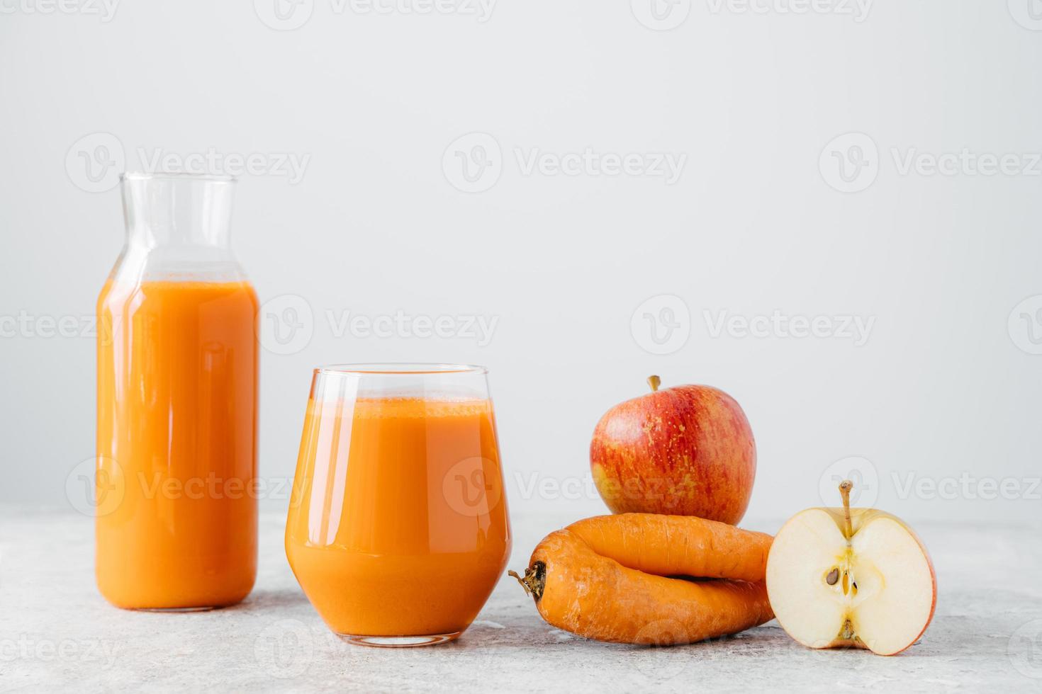 Glasses of orange juice made of carrot and apple isolated on white background. Refreshed homemade drink and ingredients. Detox beverage photo