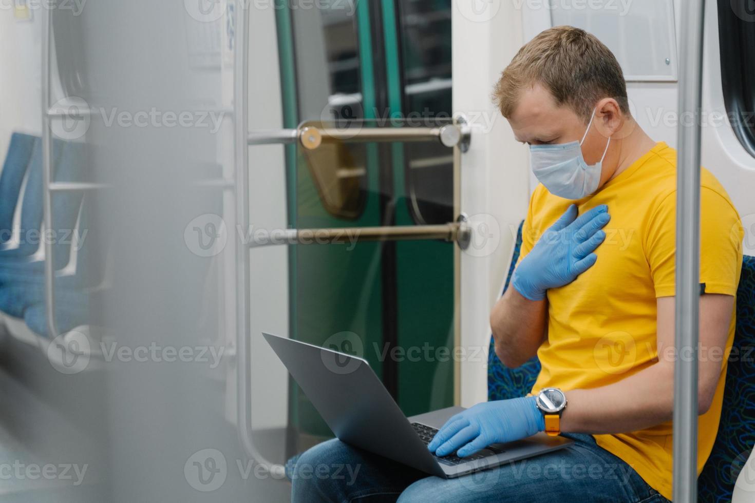 Sick man has problems with breathing, symptoms of coronavirus, concentrated in laptop computer, wears medical mask and gloves, commutes by public transport. Dangerous virus disease spreading photo