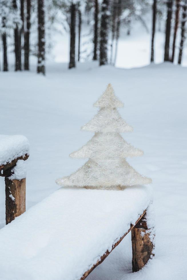 Vertical shot of white artificial fir tree on bench covered with snow, in winter frosty forest. Holidays decoration. Season concept. Holiday. Wonderful winter photo