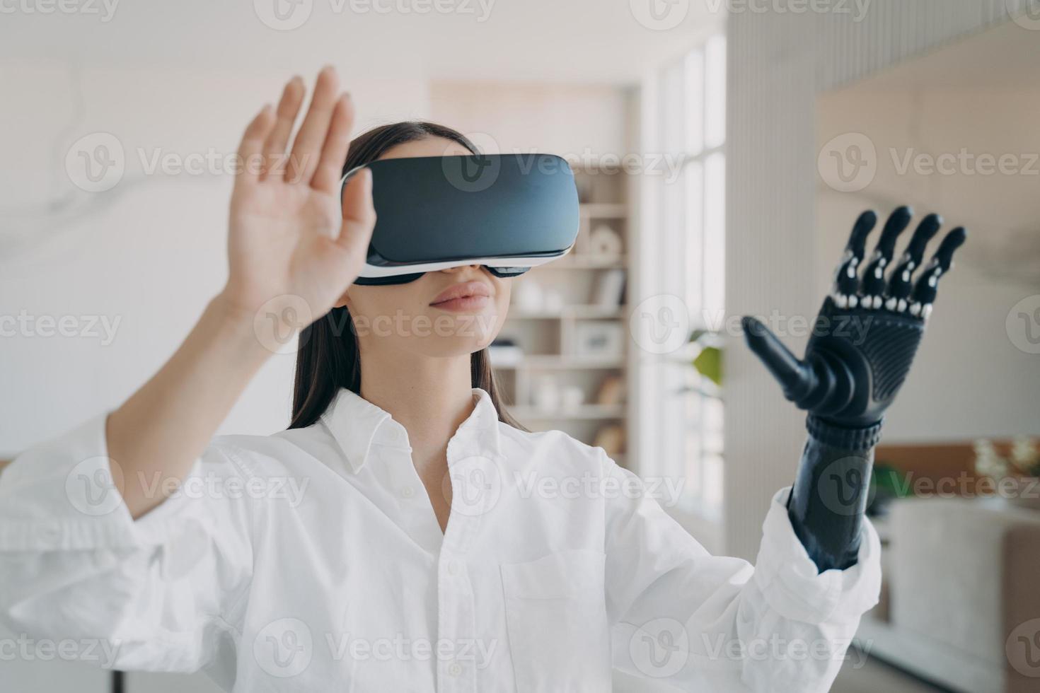 Happy handicapped girl in vr glasses at home. Woman with artificial hand is excited with 3d vision. photo