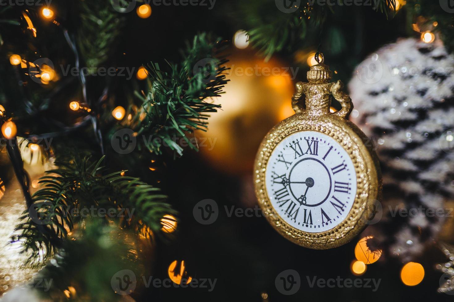 Picture of decorated New Year or Christmas tree with garlands and baubles. Decoration in form of clock symbolizes starting new year. Holidays, celebration, winter concept. photo