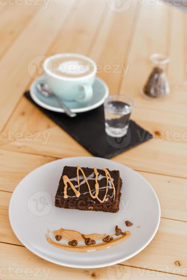 Cup of hot cappuccino coffee on table with fudge cake photo