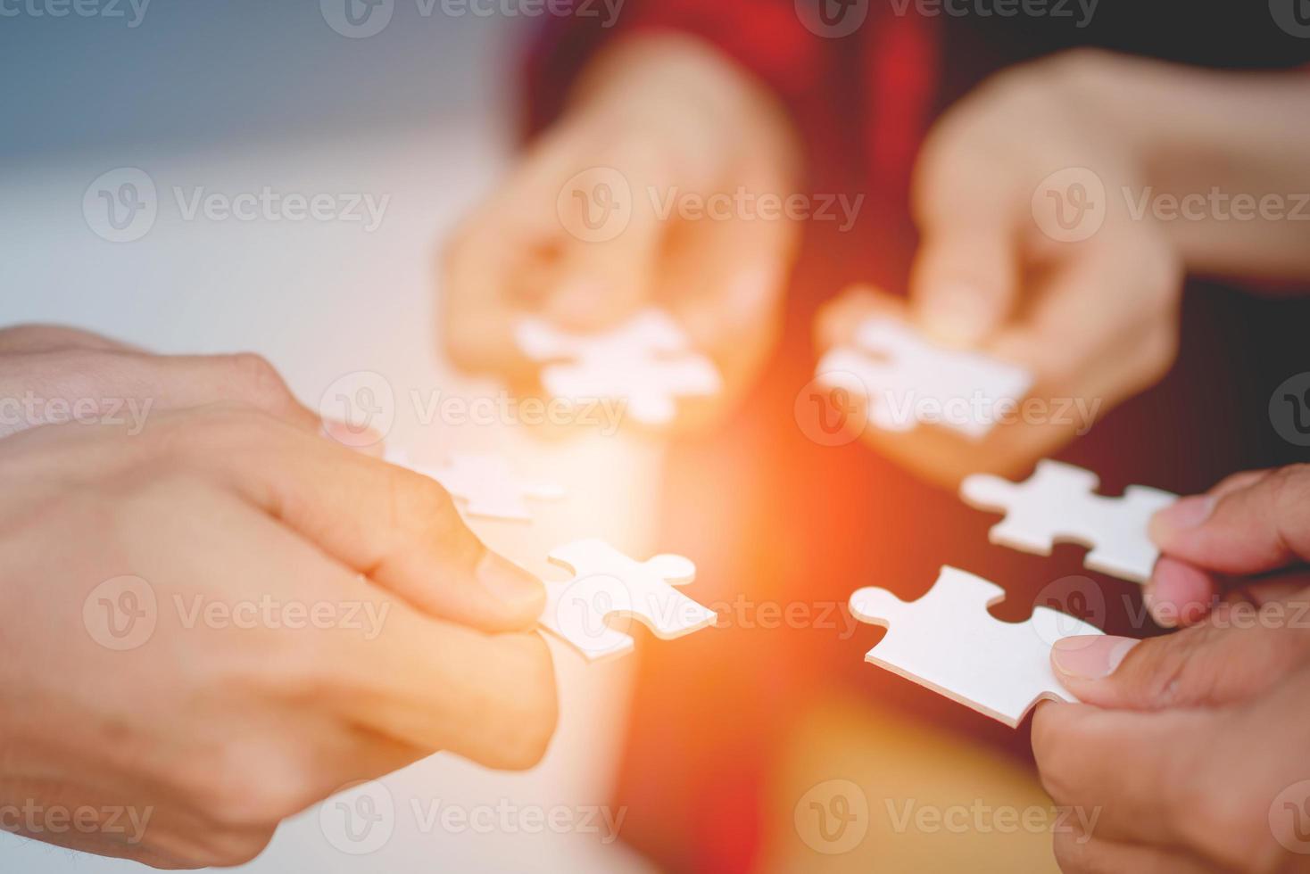 The hands of a variety of people including the Asian jigsaw puzzle And gather parts to find suitable partners to support teamwork to find common problem solving concepts, close-up perspectives photo