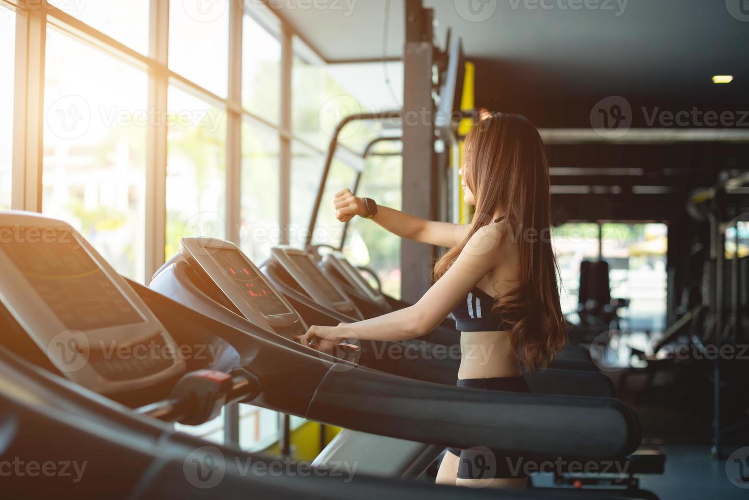 Side view of two attractive sports women on running track. Girls on treadmill photo