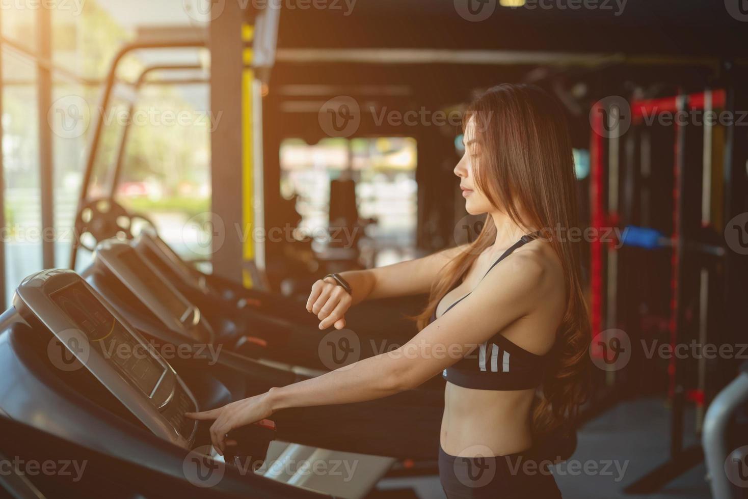 Side view of two attractive sports women on running track. Girls on treadmill photo